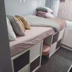 a small bed with drawers underneath it and a clock on the wall above it in a bedroom