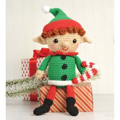 a crocheted elf doll sitting next to presents