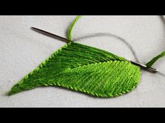 a close up of a green leaf with scissors on it's side and thread in the middle