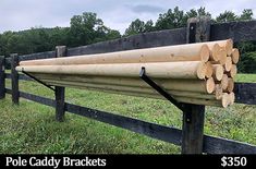 a wooden fence with logs stacked on it and the words pole caddy brackets $ 350