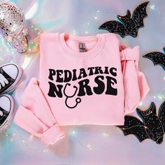 a pink shirt with the words pediatric nurse on it next to some shoes and decorations