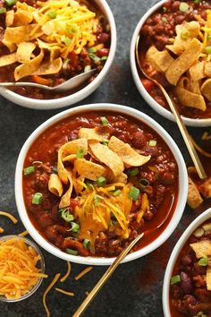 three bowls filled with chili, cheese and tortilla chips on top of a table