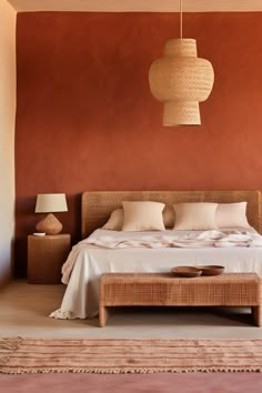 a bed with white sheets and pillows in a bedroom next to a lamp hanging from the ceiling