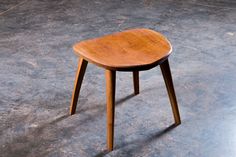 a wooden stool sitting on top of a cement floor