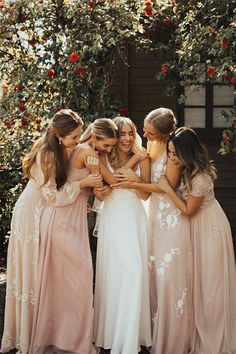 the bridesmaids are hugging each other in front of a rose - covered tree