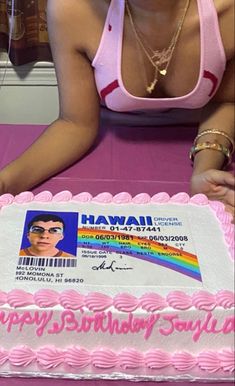 a woman sitting in front of a pink birthday cake with a barcode on it