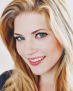 a woman with long blonde hair and blue eyes smiles at the camera while posing for a photo