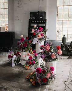 several white vases filled with colorful flowers on top of a floor next to a piano