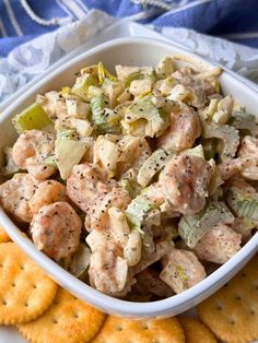 a white bowl filled with chicken salad next to crackers