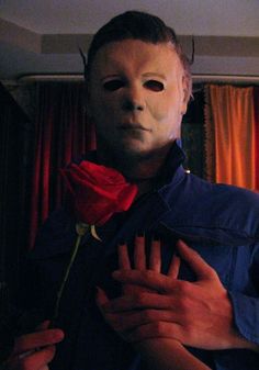 a person wearing a mask holding a rose