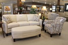 a living room filled with lots of furniture in it's center aisle and surrounded by shelves