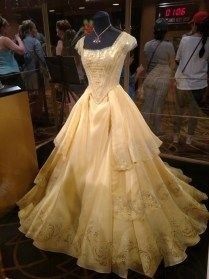 a dress on display in a glass case with people looking at the mannequins