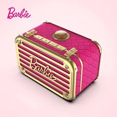 a pink and gold suitcase sitting on top of a pink surface with the word barbie above it