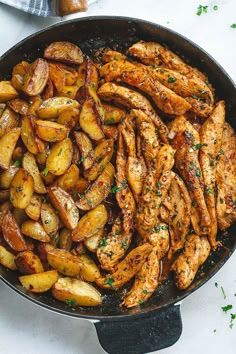 chicken and potatoes in a skillet with parsley on the side