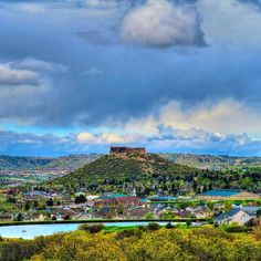 a scenic view of a city with mountains in the back ground and clouds in the sky