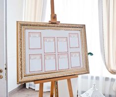 a wooden easel holding a white board with pictures on it in front of a window