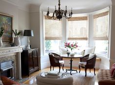 a living room filled with furniture and a fire place in front of a window covered in blinds