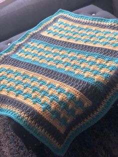 a crocheted blanket sitting on top of a couch