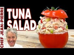 a man standing next to a large tomato with tuna salad in it's center