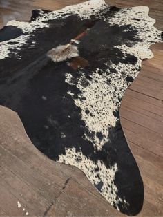 a black and white cowhide rug on wooden floor