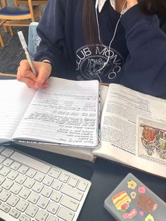 a person sitting at a desk with an open book and keyboard in front of them