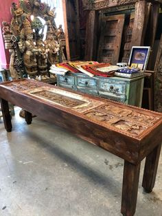 an old wooden table with carvings on it in a room filled with other antique items