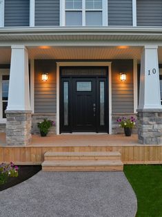 a front porch with steps leading up to the door and two lights on either side