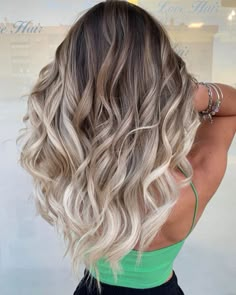 the back of a woman's head with long, wavy hair and green dress