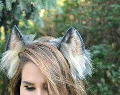 a woman with long hair wearing a cat ears headpiece in front of some trees