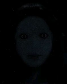 a woman's face is shown in the dark, with her eyes wide open