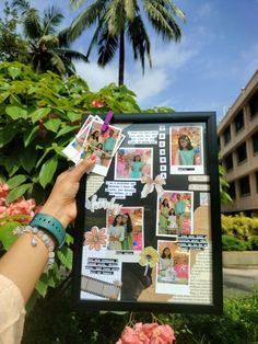 a person holding up a poster with pictures on it in front of some bushes and flowers