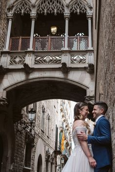 a bride and groom standing in front of an arch on the side of a building