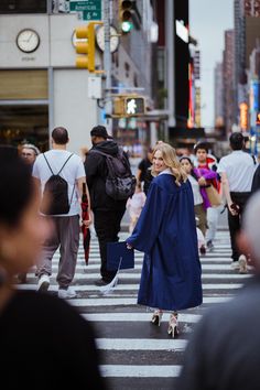 a woman walking across a cross walk in the middle of a busy city street,