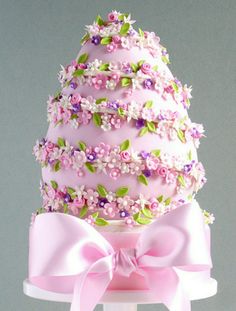 a pink cake decorated with flowers and ribbons