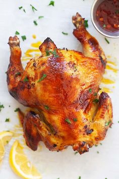 a roasted chicken on a cutting board with lemons and ketchup