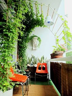 an orange chair sitting on top of a wooden floor next to a green plant covered wall