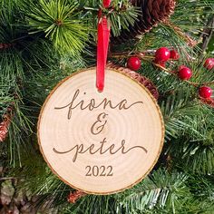 a wooden ornament hanging from a christmas tree with pine cones and red berries