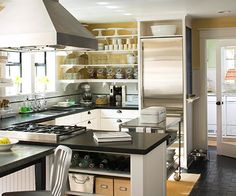 a kitchen with black counter tops and white cabinets, an island in front of the stove