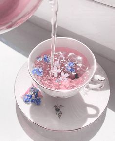 a cup filled with liquid sitting on top of a saucer next to a window