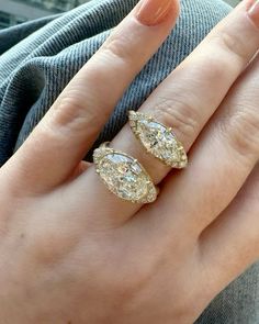 a woman's hand with two engagement rings on her left and the other hand holding another ring