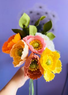 a hand holding a vase filled with colorful flowers