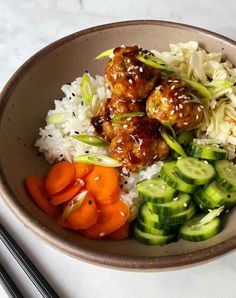 a bowl filled with rice, meatballs and veggies next to chopsticks