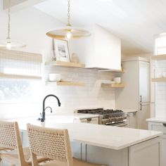 a kitchen with an island and chairs in the center, along with white walls and cabinets