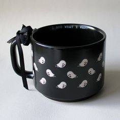 a black coffee cup with white skulls on it and a bow tie around the handle