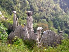 some very pretty rocks in the middle of a grassy area with trees and bushes behind them