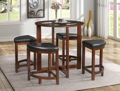 a dining table with four stools and a round glass top table in a living room