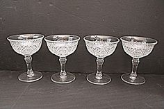 four glass goblets sitting on top of a table next to eachother