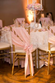 the chairs are decorated with pink sashes and bows for an elegant touch to the table