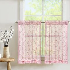 the window is decorated with pink sheer curtains