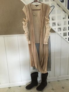 a woman standing in front of a stair case wearing a long cardigan and boots